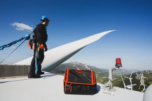 inżynier pracujący na szczycie turbiny wiatrowej